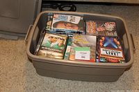 Top view of plastic tote filled with various DVDs, clearly showing Monty Python Live!, We Are Marshall, X-Files DVD cases and more.