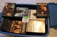 Blue plastic storage container filled with multiple DVDs showing a few titles on top including The Bone Collector and The Transporter.
