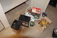 Overhead view of all handyman items including soldering iron, storage containers, tapes, and hardware supplies