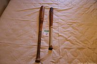 Two vintage wood baseball bats laid flat on white cloth surface, long shot