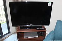 Samsung 43 inch TV front view with remote on TV stand and DVD player below it