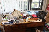Wide view of the wooden desk with assorted tools and hardware items piled on top including electrician belts and tool bags.