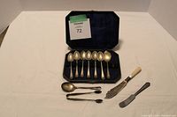 Full set of silver plated teaspoons in original blue velvet lined box with serving knives and tongs in front