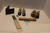 Full lot of vintage items including two pairs of vintage baby shoes, leather wallet, wood ruler, calculator, and brass turtle figurine on white background.