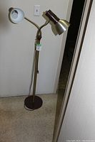 Full view of vintage dual-arm standing floor lamp with two adjustable arms and metal shades, round base.