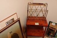 Side view of the vintage wood side table with the metal magazine rack placed on top, showing the two-tier table and the geometric metal rack design.