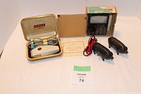Overall photo showing all items including two piggy banks, electric razor in case, and multi-meter with box and manual.