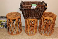 Photo showing three vintage wicker end tables and two dark brown wicker baskets with wooden handles, arranged on a carpeted floor.