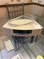 Bose stereo system with remote control on glass table, beige color, black front panel, Bose logo visible.