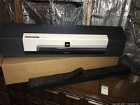 Bose Soundbar 700 in front of original printed box and plain cardboard box