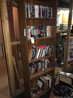 Wooden bookshelf loaded with assorted DVD cases and books on multiple shelves