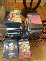 Two stacks of DVDs and Blu-ray discs on floor showing various titles