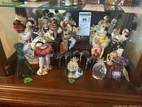 Full set of porcelain, wooden figurines and crystal cactus on wooden cabinet shelf