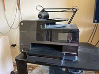 Front-right angle of HP OfficeJet Pro 8620 printer showing paper output tray, LCD display and scanner lid.