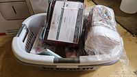 Laundry basket containing sheets, throws and socks in packaging.
