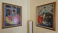 Wide view showing both framed needlepoint artworks hanging on a wall.