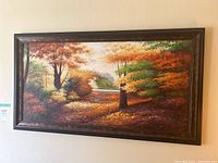 Front view of the framed landscape painting showing autumn trees and a river.