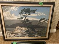 Framed print showing stylized trees, rocks and cloudy sky in muted colors with wood/gold frame, 18x24 inches