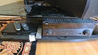 Photo showing Yamaha RX-A550 receiver alongside Panasonic DMP-BDT270 Blu-ray player with their remote controls on top.