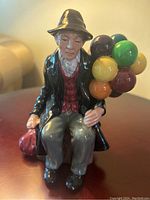 Front view of Royal Doulton Balloon Man figurine showing detailed facial features, multi-colored balloons, and seated position.