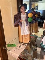 Front view of Royal Doulton Balloon Lady figurine on glass shelf.