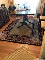 Full view of rectangular area rug under dining table surrounded by chairs and furniture.