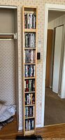 Front view of tall wooden shelving unit, showing seven shelves filled with DVDs (not included).