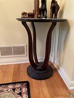Side view of the dark wood round side table with curved legs and circular base, showing the shape and structure.