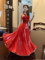 Front side view showing detailed flowing red dress and holding glass