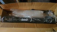 Bushnell telescope in original packaging, wrapped in plastic inside a cardboard box with visible wear and water damage