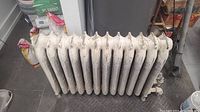 Side-angle view of 12 section cast iron radiator showing 12 vertical cast iron sections and white paint wear