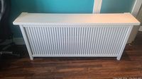 Front view of the custom MDF radiator cover showing vertical slats and white finish.