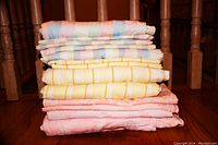 Photo of the 6 folded duvet covers in various pastel colors and patterns, stacked on a wooden floor.