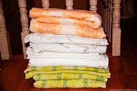 Stack of six folded duvet covers with pillow cases in varying colors and floral designs