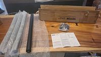 Four metal table legs wrapped in bubble wrap, instruction sheet, mounting hardware, and original box displayed on wooden table.
