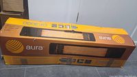 Box of Aura CF3000 electric patio heater showing front and branding with damaged packaging.