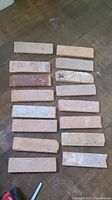 Multiple individual rectangular reclaimed brick veneer pieces arranged on floor showing color variations and weathered texture.