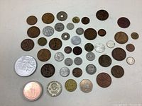 Top-down image showing the entire collection of 42 assorted coins laid out flat on a surface, exhibiting variety in size, shape, and metal tones.