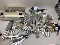Image showing large assortment of knives, forks, spoons and serving utensils in silver tone metal with varying handle designs.
