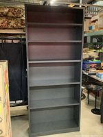 Front view of tall grey office bookcase showing six shelves, empty