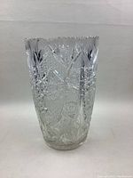 Front view of large vintage cut crystal vase showing detailed cut patterns and scalloped rim with minor chip.