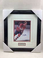Framed 8x10 photograph of hockey player Guy Lafleur wearing a Montreal Canadiens uniform skating on ice, autographed on the photo, with black frame and protective corners.