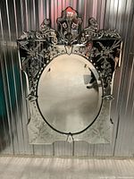 Front view showing entire mirror with oval center and decorative etched panels