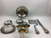 Overview of sterling silver items including plates, bowls, cups, coasters, carving set, toast rack