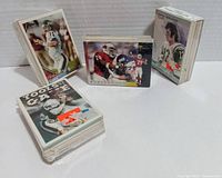Photo showing four stacks of assorted football cards with snapshots of individual cards showing players in action and rookie designations.