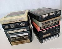 Front and side view of stacked 8-track tapes showing artist and album titles.