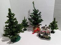 View of four miniature pine trees with artificial green foliage on assorted bases and ceramic coffee store with Santa.