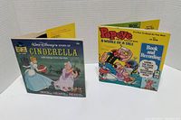Front cover of Walt Disney's Story of Cinderella book and Popeye A Whale of a Tale book with colorful illustrated covers and titles.