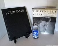 Photo showing the front covers of two hardcover JFK books 'FOUR DAYS' and 'THE KENNEDY YEARS', along with the commemorative JFK glass.