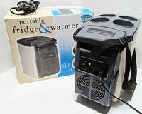 Portable mini fridge cooler & warmer with cup holders on top, carrying strap, and power cord attached. Box visible in background.